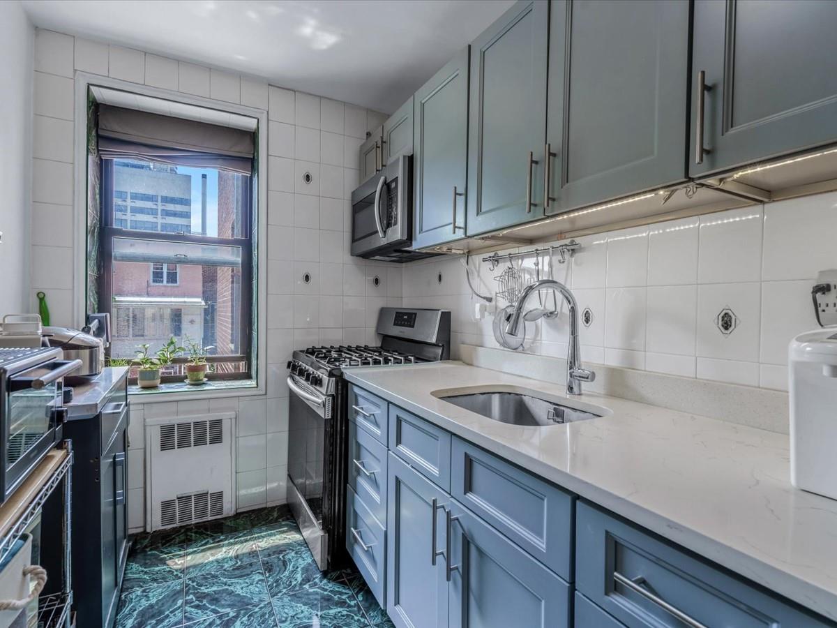102-12 65th Avenue, Unit D22 Queens, NY 11375 - Photo 7 of 12 a kitchen with stainless steel appliances granite countertop a sink stove and cabinets