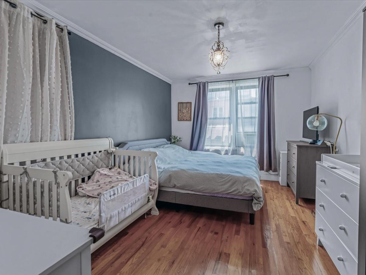 102-12 65th Avenue, Unit D22 Queens, NY 11375 - Photo 8 of 12 a bedroom with a bed and a chandelier