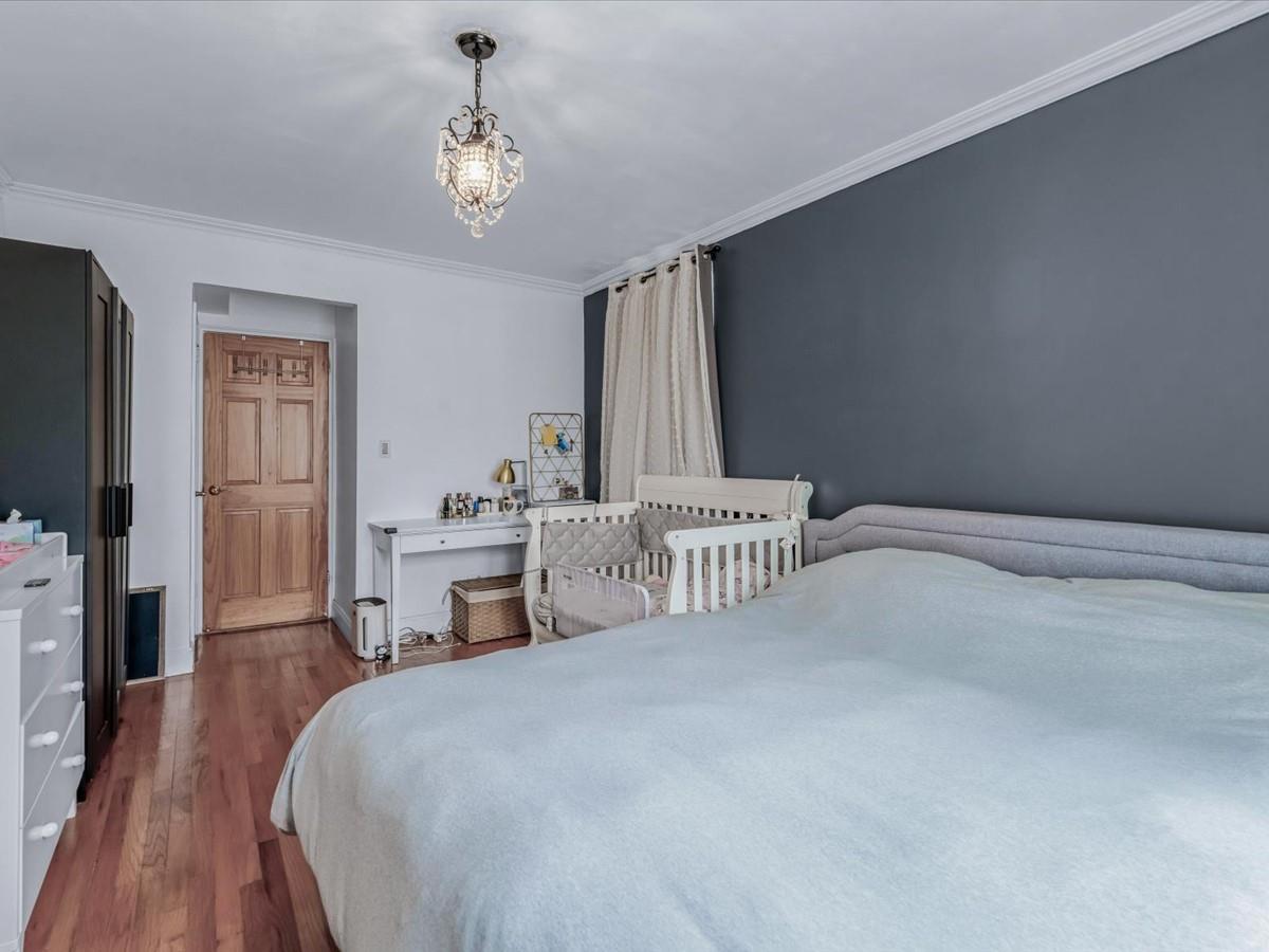 102-12 65th Avenue, Unit D22 Queens, NY 11375 - Photo 9 of 12 a bedroom with a bed and a chandelier