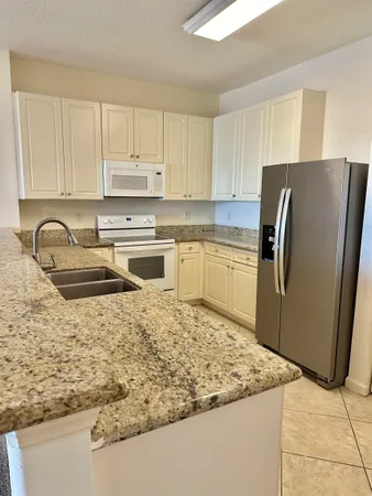 a kitchen with stainless steel appliances granite countertop a refrigerator and a stove