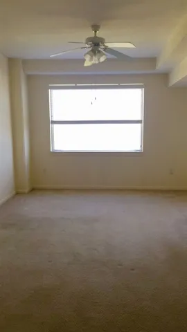 an empty room with a window and ceiling fan