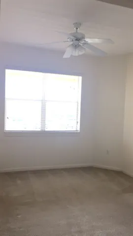 an empty room with a window and a fan