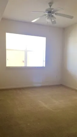 an empty room with a window and a fan