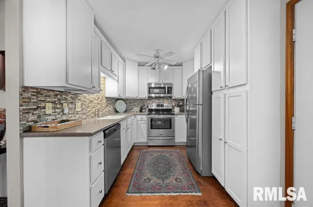 a kitchen with stainless steel appliances granite countertop a sink a stove a refrigerator cabinets and a window