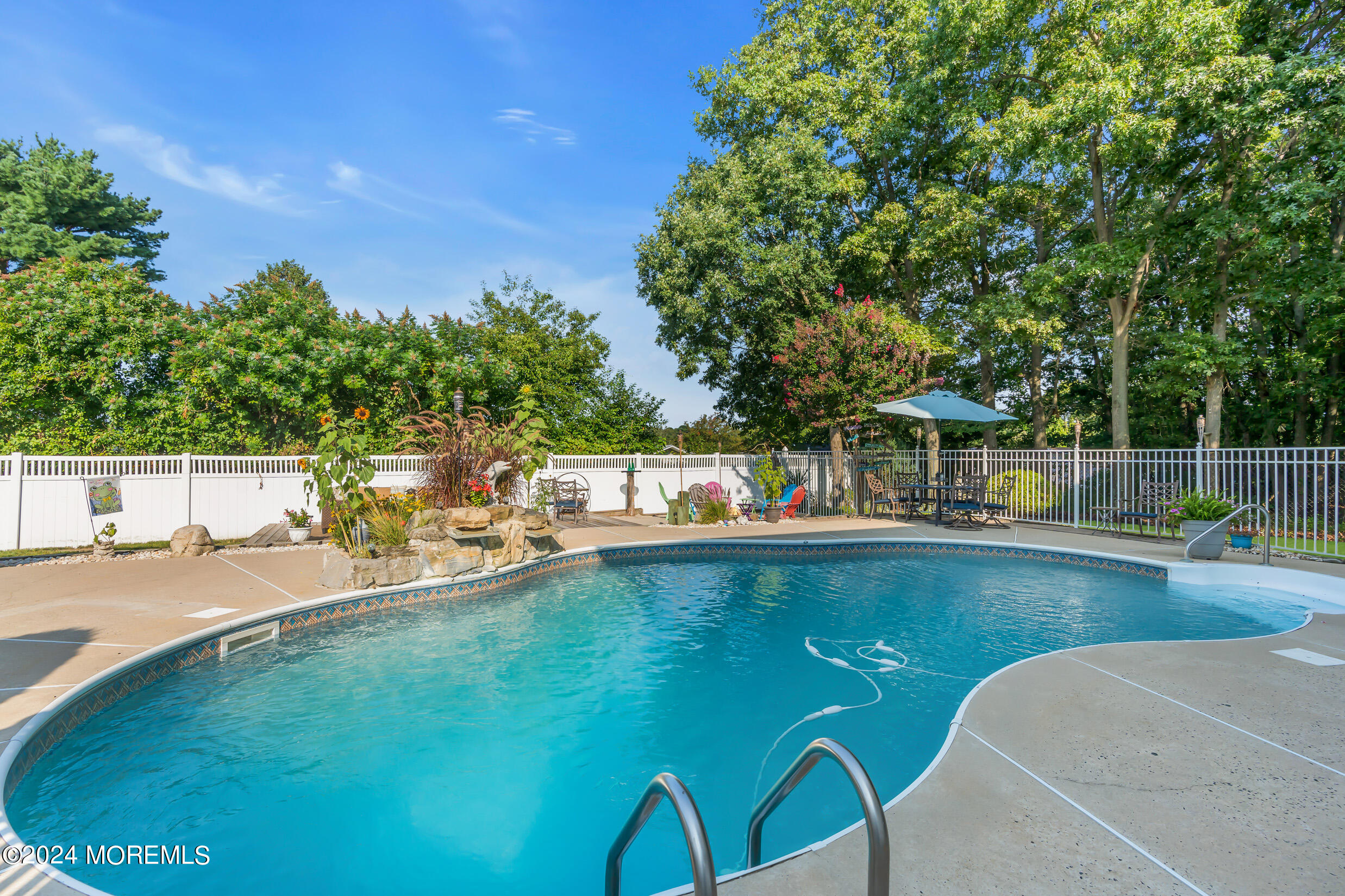 24 Ryjac Court Brick, NJ 08724 - Photo 40 of 57 a view of a swimming pool with a bench and trees in the background