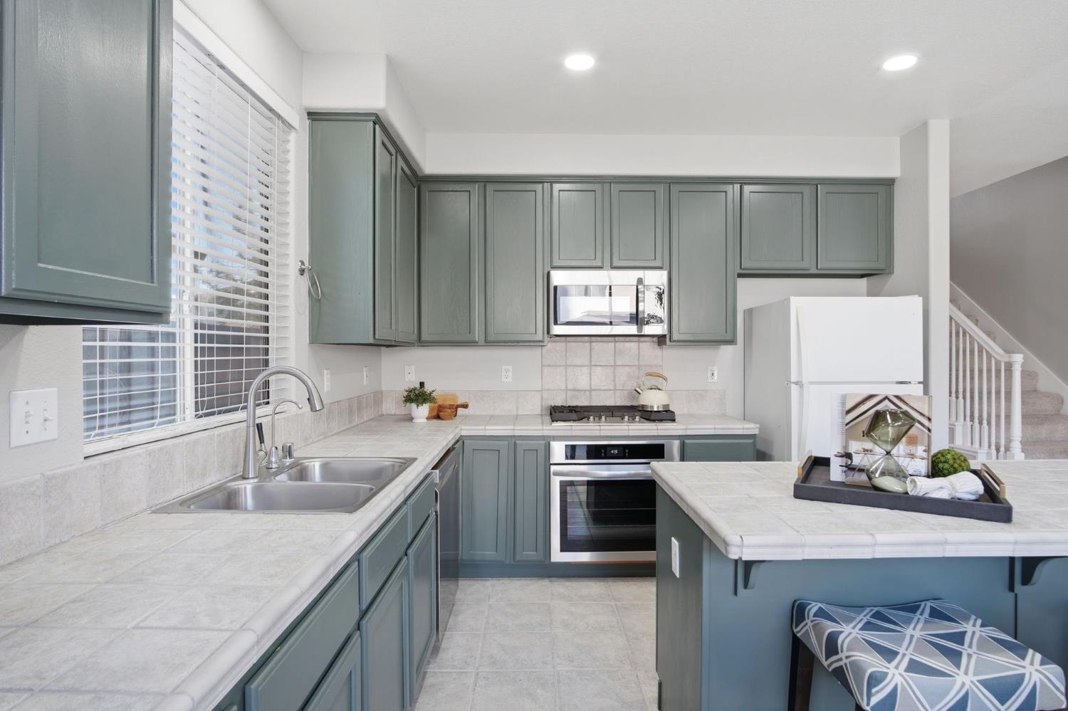 2403 Clemente Lane Tracy, CA 95377 - Photo 12 of 43 a kitchen with stainless steel appliances granite countertop a sink stove refrigerator and cabinets