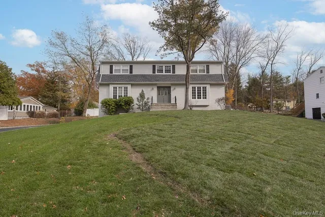 a view of a white house next to a yard with big trees