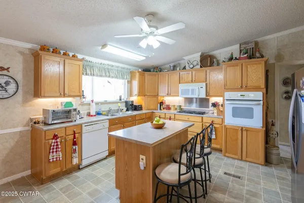 a kitchen with stainless steel appliances granite countertop a table chairs sink refrigerator and cabinets