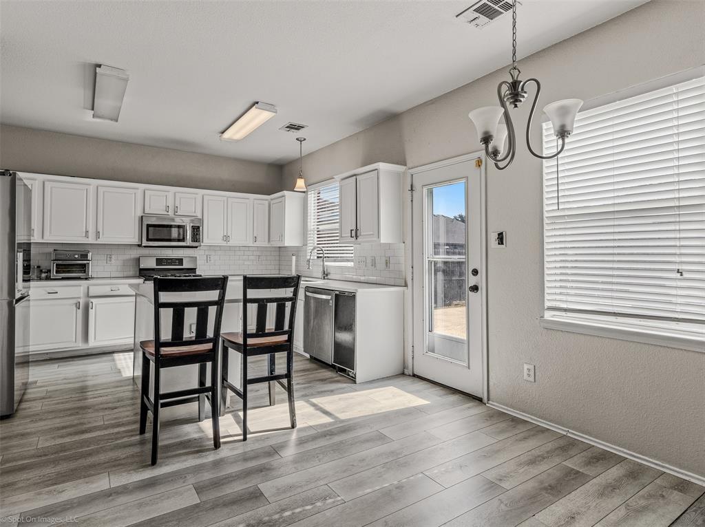 503 Pinto Lane Forney, TX 75126 - Photo 7 of 20 a kitchen with stainless steel appliances granite countertop a refrigerator a sink dishwasher a stove and white cabinets with wooden floor