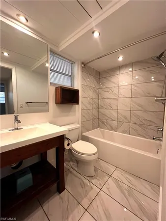 a bathroom with a sink a toilet a mirror and bathtub