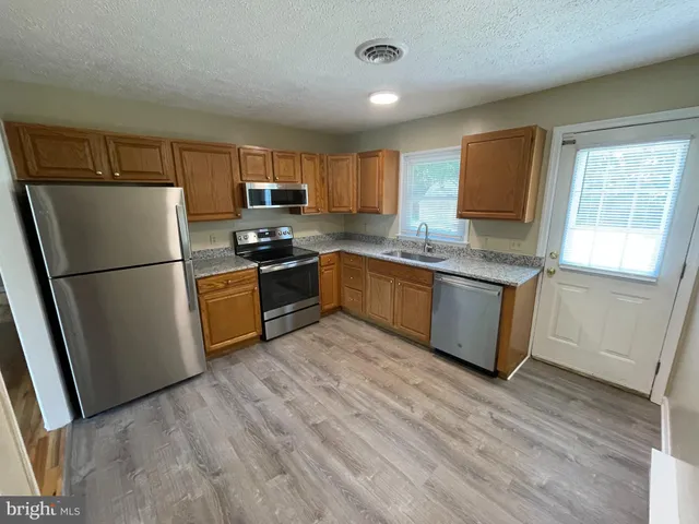 a kitchen with stainless steel appliances granite countertop a refrigerator a stove a sink dishwasher and a refrigerator