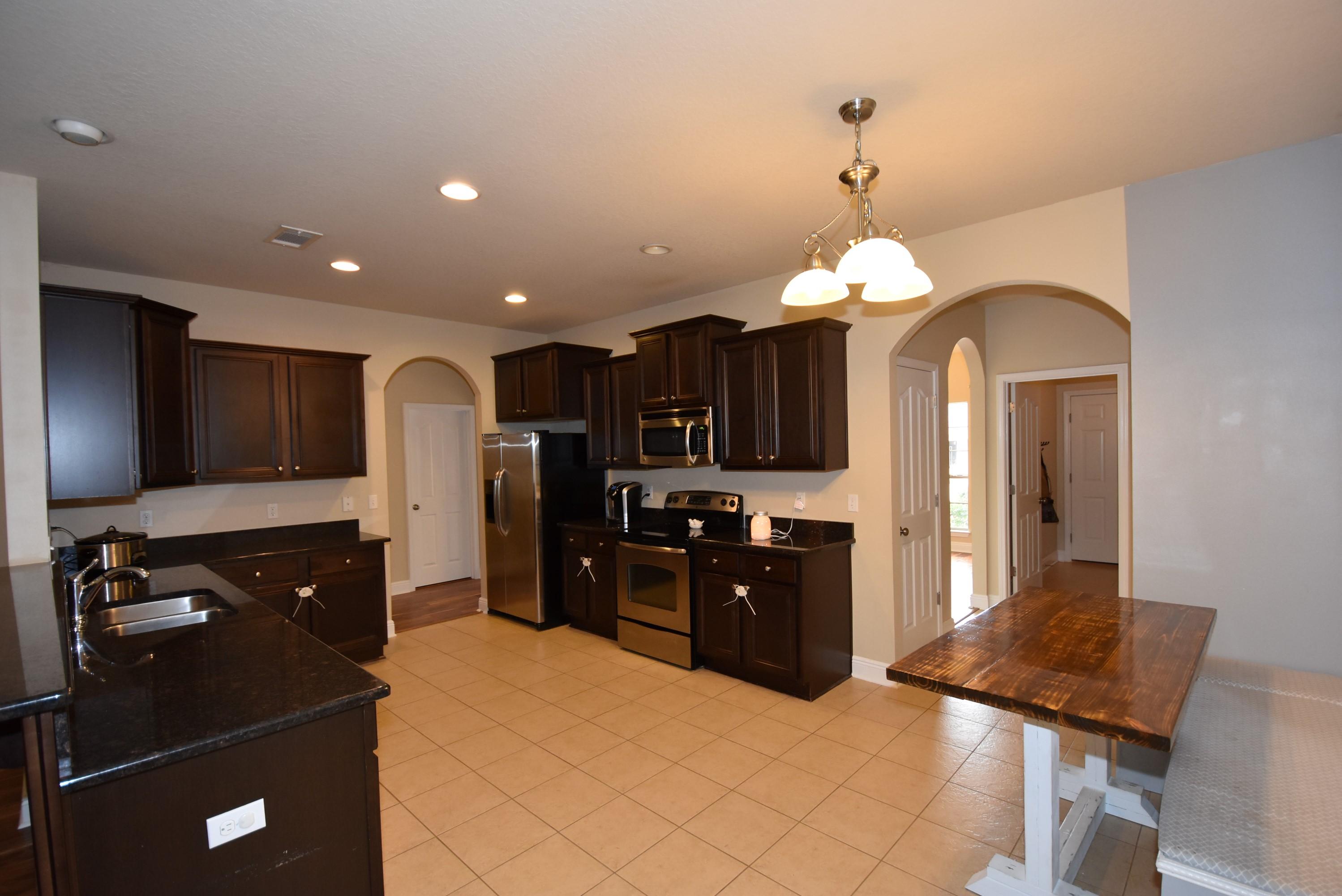 640 Red Fern Road Crestview, FL 32536 - Photo 14 of 50 a kitchen with stainless steel appliances granite countertop a refrigerator a sink dishwasher and a stove with wooden floor