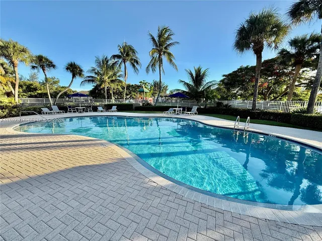 a view of a swimming pool with a chair and palm trees