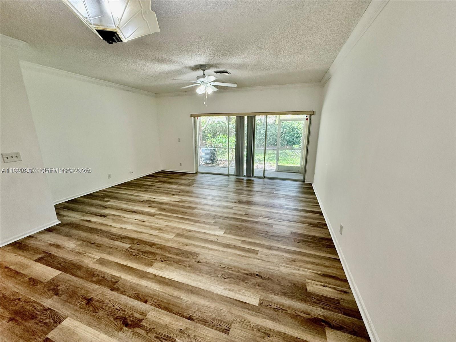 4855 Palmbrooke Circle, Unit 4855 West Palm Beach, FL 33417 - Photo 21 of 40 a view of an empty room with wooden floor and a window