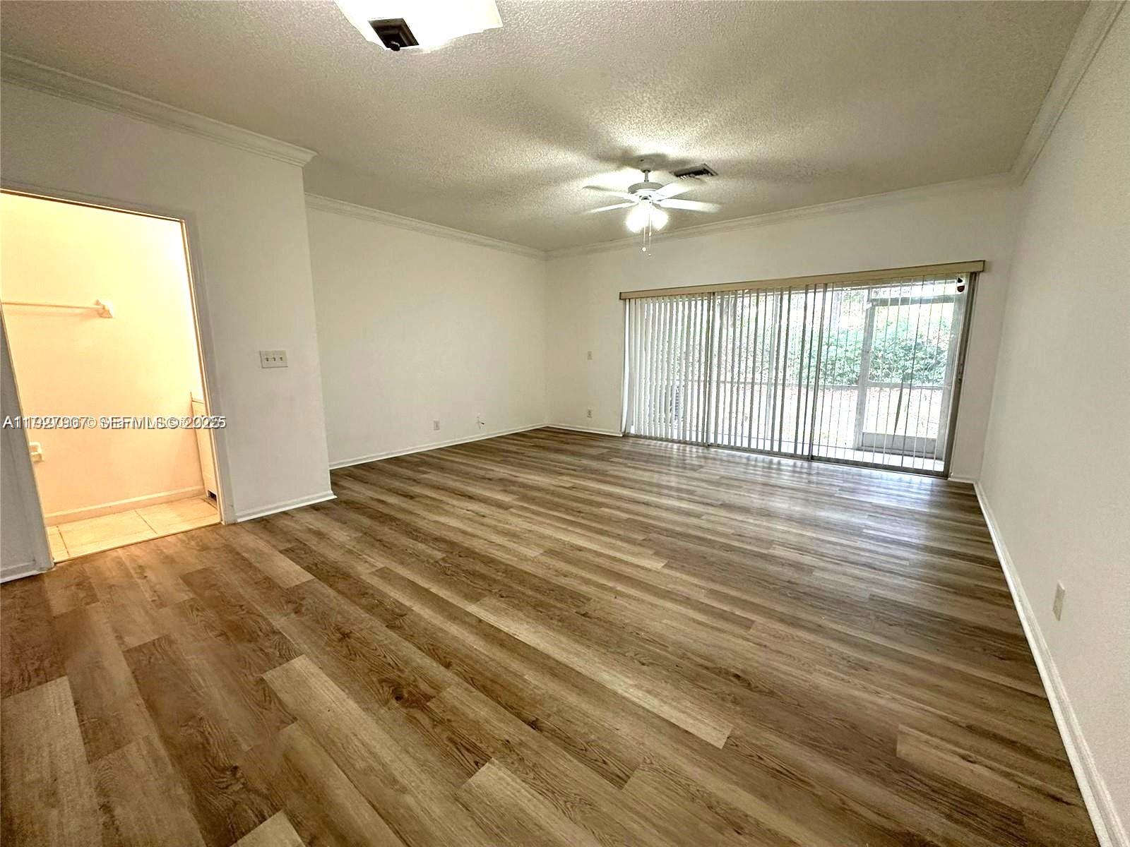 4855 Palmbrooke Circle, Unit 4855 West Palm Beach, FL 33417 - Photo 22 of 40 a view of an empty room with wooden floor and a window