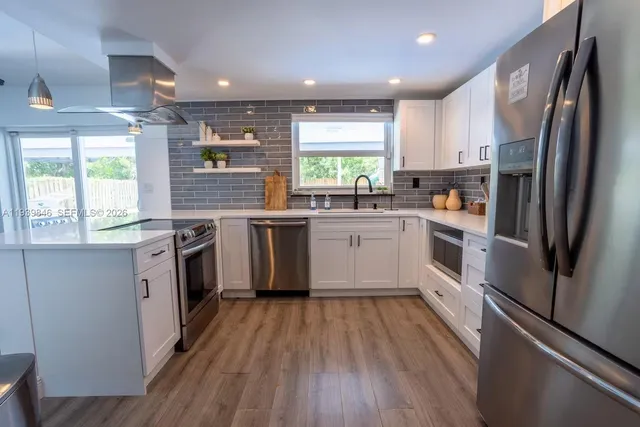 a kitchen with white cabinets stainless steel appliances and window