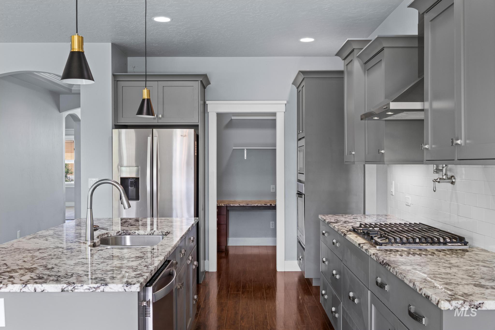 2681 East Rhyolite Court Nampa, ID 83686 - Photo 13 of 48 Kitchen featuring grey shaker cabinetry, stainless steel appliances, a gas cooktop, stone countertops, and wood-finish flooring