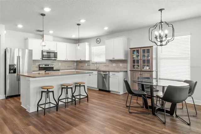 a kitchen with stainless steel appliances a dining table chairs and wooden floor