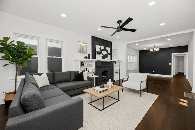 a view of a livingroom with a fireplace a ceiling fan and wooden floor