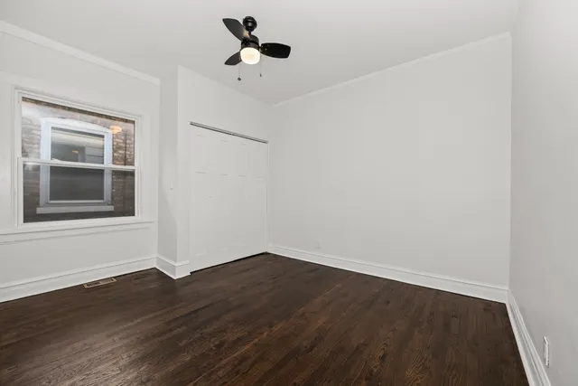 a view of an empty room with wooden floor and kitchen