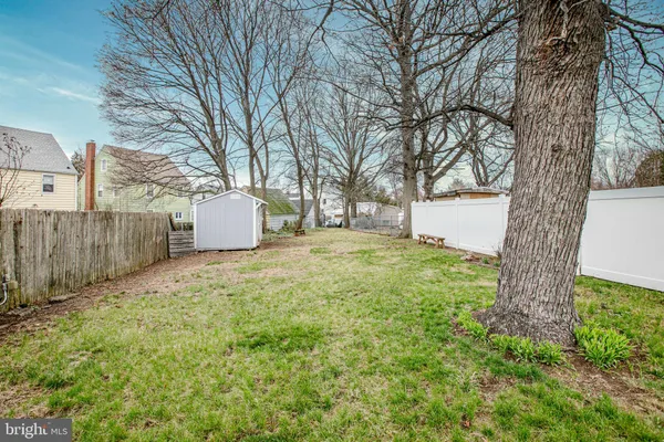 a backyard of a house with a large tree and wooden fence