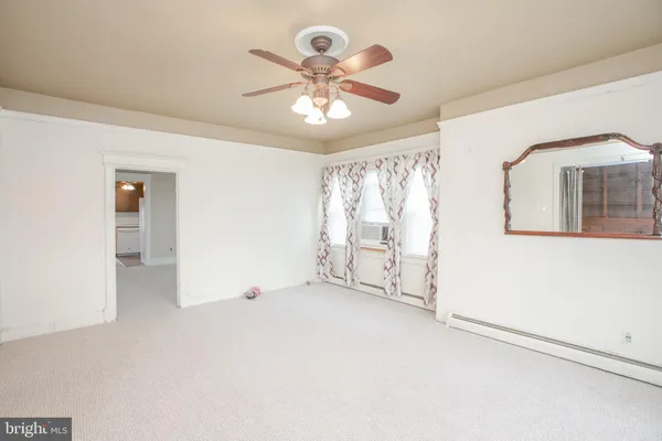 an empty room with chandelier fan and windows