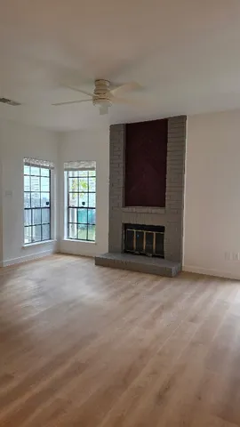 a view of an empty room with a fireplace and a window
