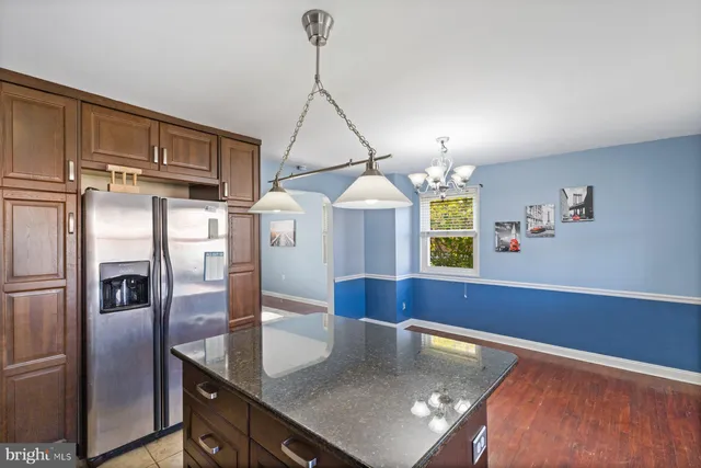 a kitchen with stainless steel appliances granite countertop a refrigerator a stove and a sink with wooden floor