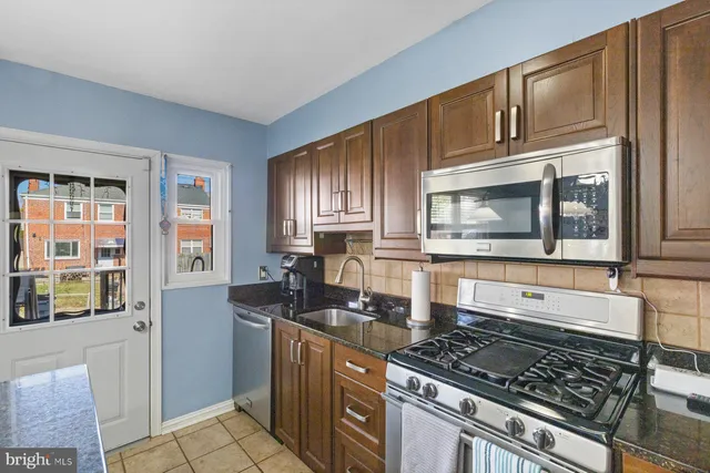 a kitchen with stainless steel appliances granite countertop a stove a sink and a microwave