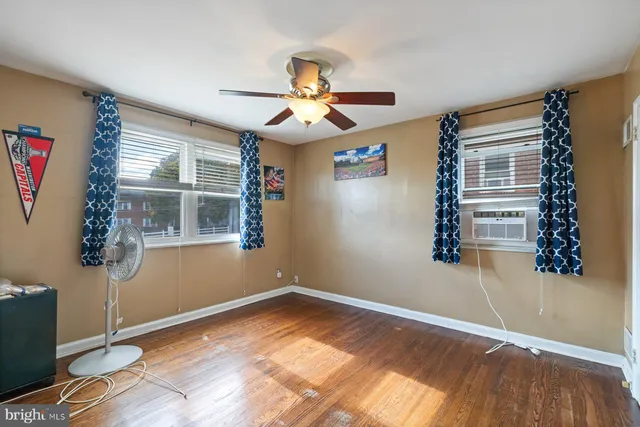 a view of empty room with wooden floor and fan