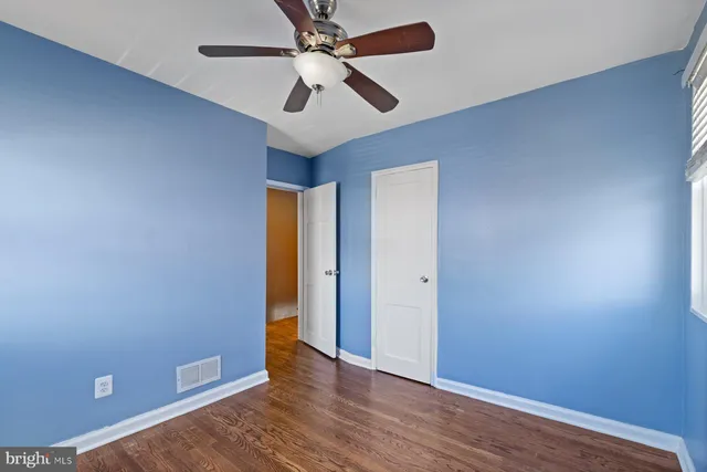 an empty room with wooden floor and a ceiling fan