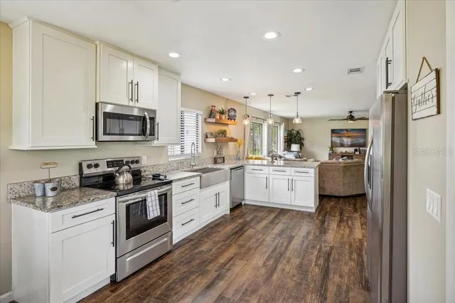 a kitchen with stainless steel appliances granite countertop a stove a sink a oven a dining table and chairs with wooden floor