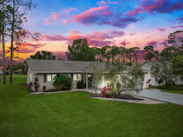 a view of a house with a big yard potted plants and a large tree