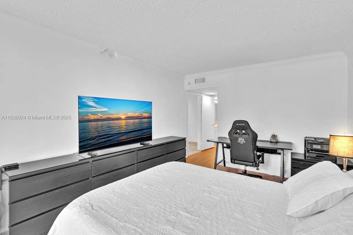 8855 Collins Avenue, Unit 2F Surfside, FL 33154 - Photo 30 of 79 a bedroom with furniture and a flat screen tv