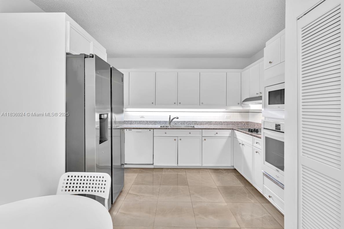 8855 Collins Avenue, Unit 2F Surfside, FL 33154 - Photo 58 of 79 a kitchen with stainless steel appliances a refrigerator sink and cabinets