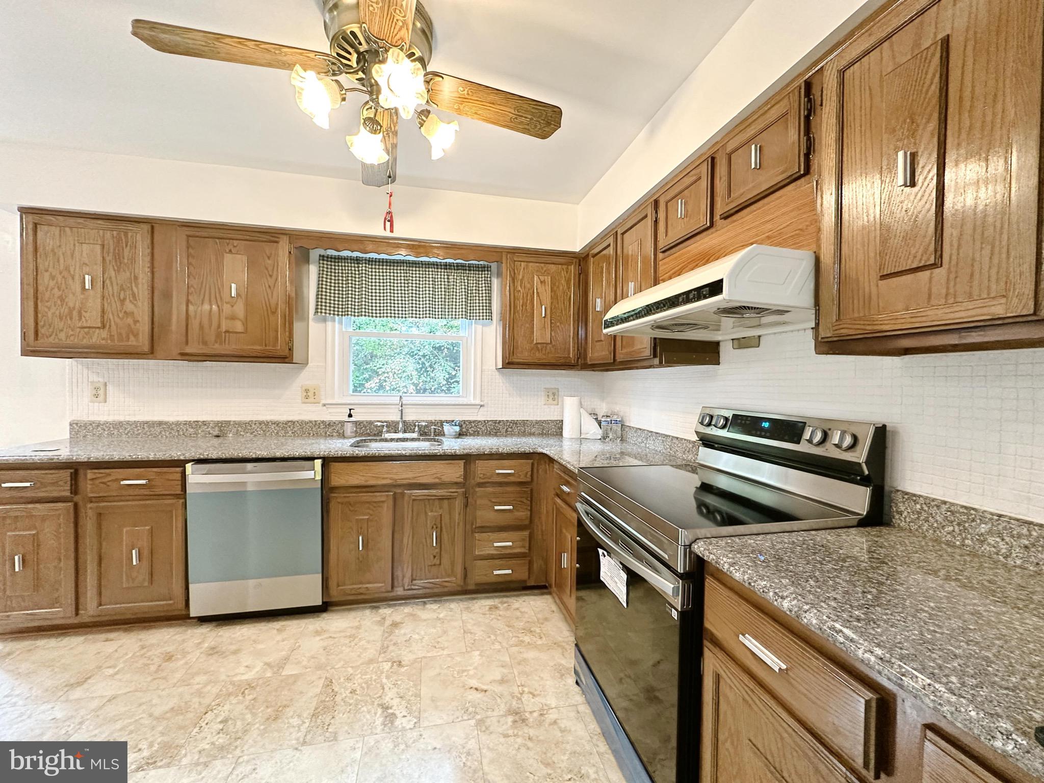 6260 Rathlin Drive Springfield, VA 22152 - Photo 6 of 27 a kitchen with stainless steel appliances granite countertop a sink a stove a chimney a refrigerator and cabinets