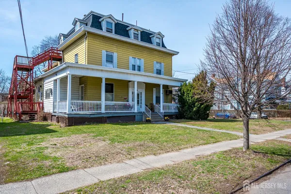 a front view of a house with a garden and trees