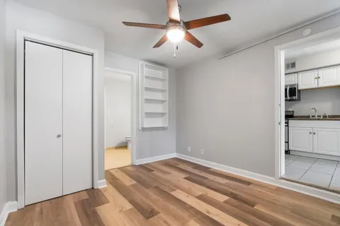 a view of empty room with wooden floor and ceiling fan