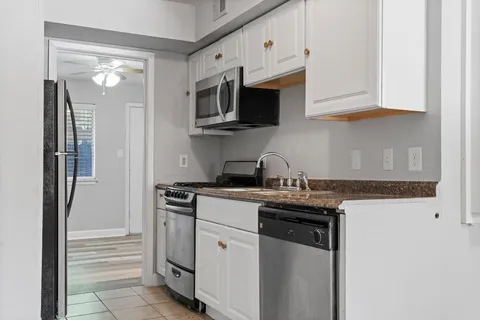 a kitchen with stainless steel appliances granite countertop white cabinets and a stove