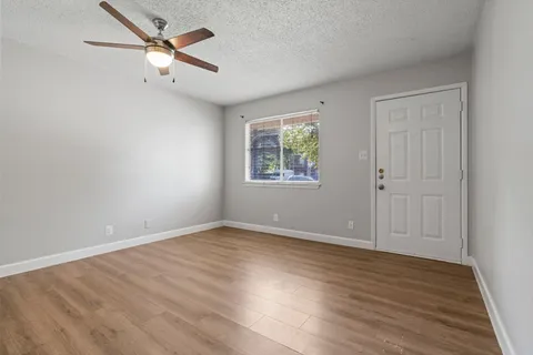 an empty room with wooden floor ceiling fan and windows