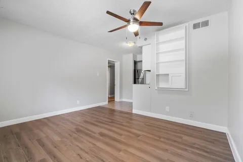 an empty room with wooden floor and a ceiling fan