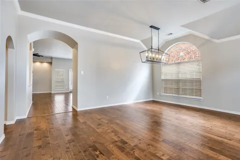 an empty room with wooden floor fan and window