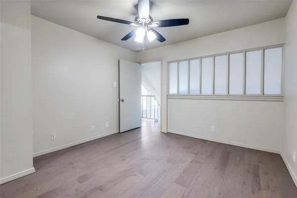 an empty room with wooden floor and fan
