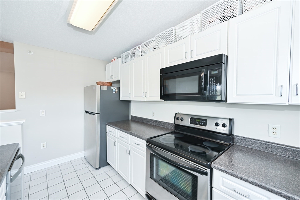 84 Mill Street, Unit 304 Woonsocket, RI 02895 - Photo 11 of 25 a kitchen with granite countertop a stove and a microwave
