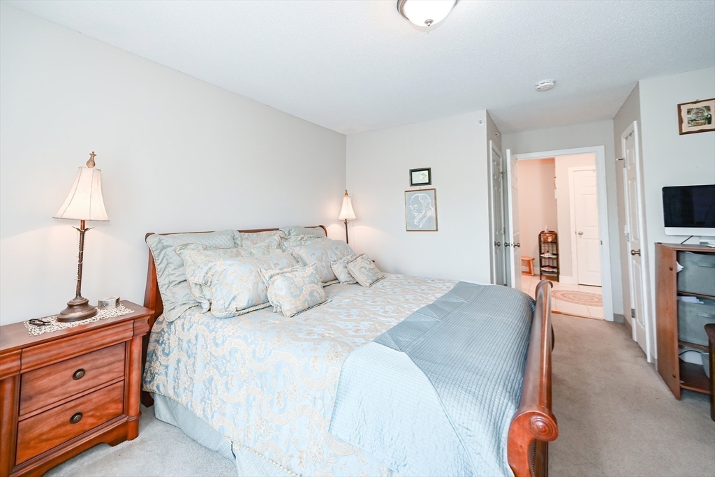 84 Mill Street, Unit 304 Woonsocket, RI 02895 - Photo 14 of 25 a bedroom with a bed and a flat tv screen on dresser