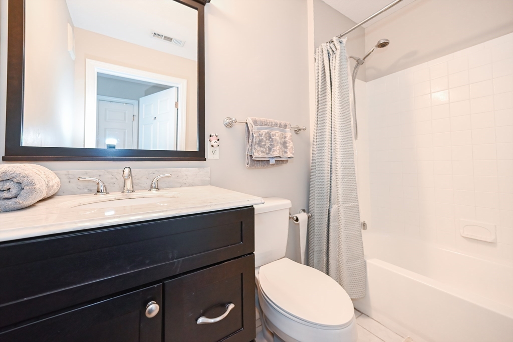 84 Mill Street, Unit 304 Woonsocket, RI 02895 - Photo 15 of 25 a bathroom with a granite countertop sink toilet a mirror and shower