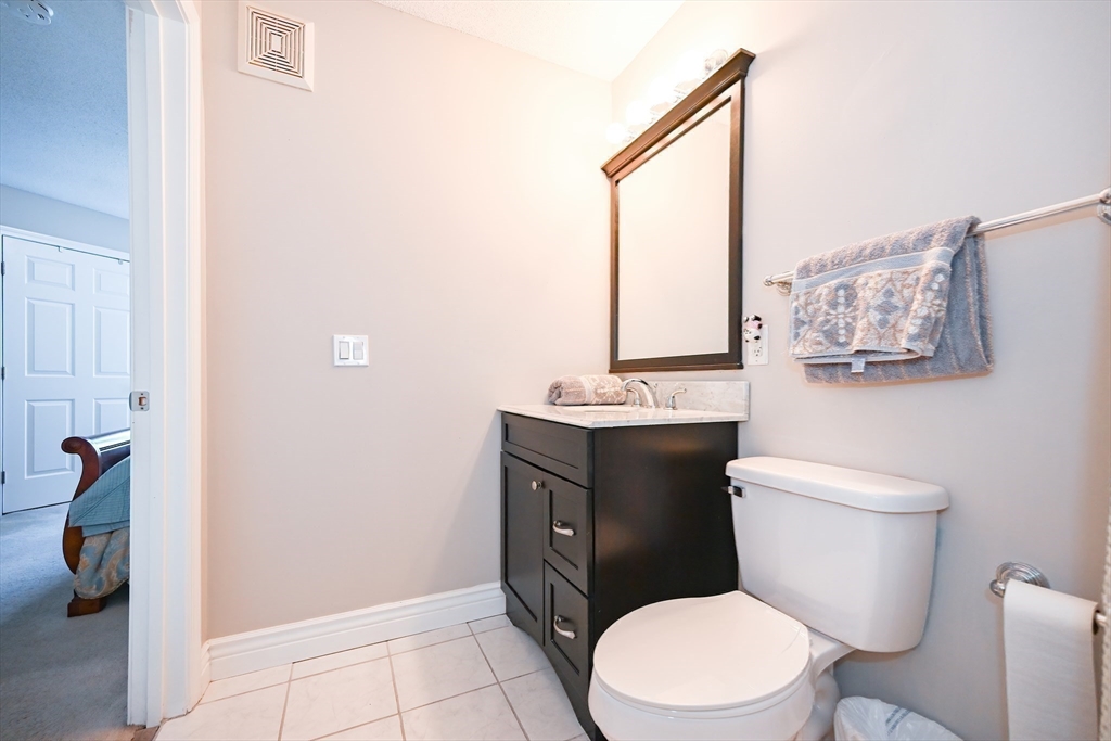 84 Mill Street, Unit 304 Woonsocket, RI 02895 - Photo 16 of 25 a bathroom with a toilet a sink and mirror