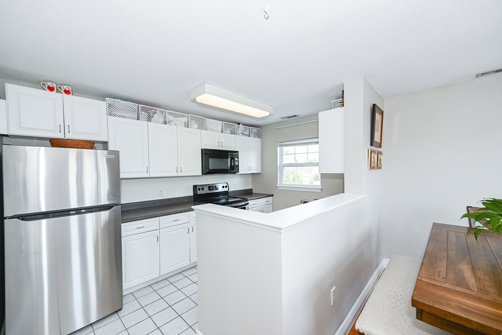 84 Mill Street, Unit 304 Woonsocket, RI 02895 - Photo 9 of 25 a kitchen with white cabinets and refrigerator