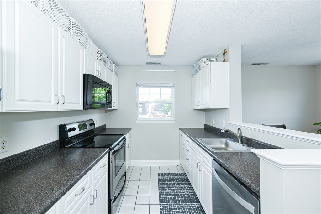 84 Mill Street, Unit 304 Woonsocket, RI 02895 - Photo 10 of 25 a kitchen with a sink stove top oven and cabinets
