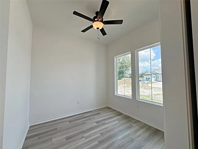 a view of empty room with wooden floor and fan